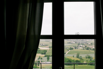 Beautiful landscape opens behind a window at which wedding rings