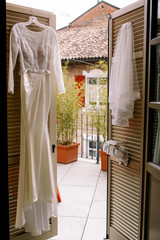 Elegant wedding gown and veil hang on the doors to the balcony