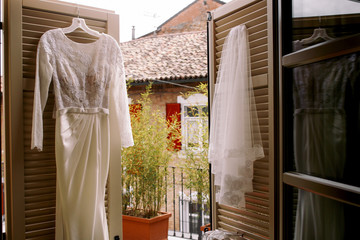 Wedding gown hangs on the wooden doors to the balcony
