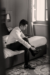 Look from behind the door at a young brunette man lacing up his