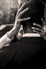 Woman with deep sparkling eyes looks from behind man's shoulder