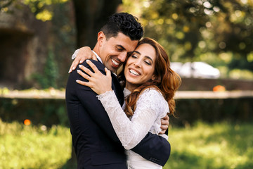 Groom closes his eyes while holding curly bride tightly in his a