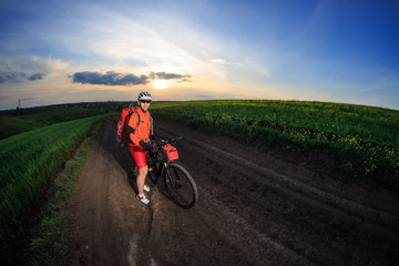 Mountain bikeer rides on the trail against beautiful sunset