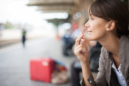femme qui fume sur le quai d'une gare
