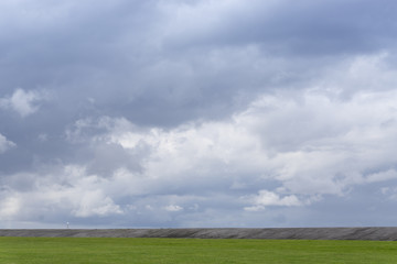 Fototapeta na wymiar Dunkle Wolken über dem Deich, Norddeich, Ostfriesland, Niedersachsen, Deutschland