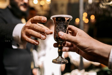 Man gives to another Jew a silver glass with drink