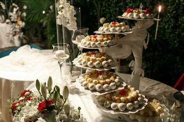 Plates with tasty sweets stand on the white buffet