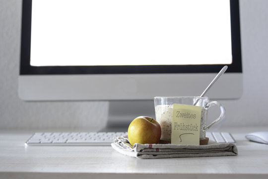Glass of porridge with linseed, chia seed and an apple on desk