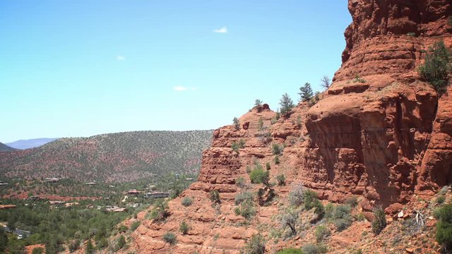 Red cliffs of mountains in Sedona, Arizona, wide angle shot, slow traffic in the distance with light mirages and air flickering cased by high temperature and fluctuations in the air density