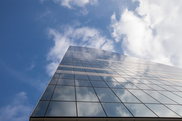 Fototapeta na wymiar Modern office building on sky background with clouds reflection