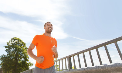 happy man with earphones running outdoors