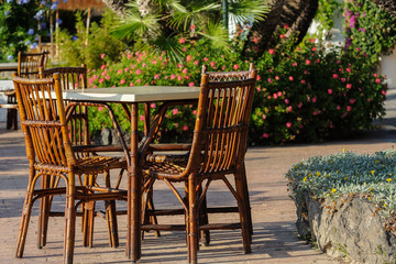 Obraz premium Tables and wicker chairs with straw sunshades in the restaurant