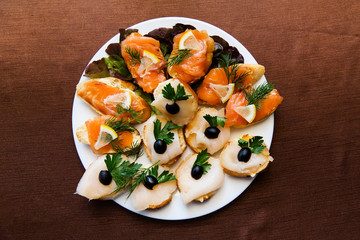 Appetizer sliced fish on a platter on the table in the restaurant, top view