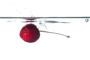 Fototapeta na wymiar Closeup of cherry falling in water, isolated on white background