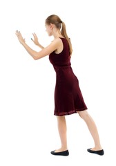 back view of woman pushes wall. Isolated over white background. Rear view people collection. backside view of person. Blonde girl in a burgundy dress leaned on something.