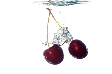Fototapeta na wymiar Cherries falling into water with splash
