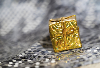 Golden Christmas gift box on silver glittering background
