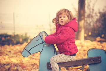 Baby girl playing with yellow leafs in autumn
