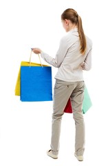 back view of woman with shopping bags . beautiful brunette girl in motion.  backside view of person.  Rear view people collection. Isolated over white background. Girl in gray jeans holding at arm's