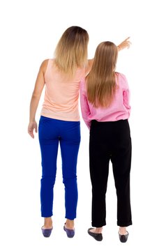 Back view of two pointing young girl. Rear view people collection. backside  view of person. beautiful woman friends showing gesture. Rear view.  Isolated over white background. One girl shows another Stock Photo