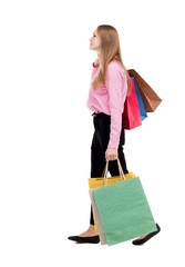 back view of going  woman  with shopping bags . beautiful girl in motion.  backside view of person.  Rear view people collection. Isolated over white background. The girl in a pink shirt with bags