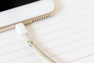 close up broken charger cable on spiral notebook