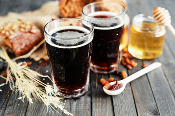 
summer and autumn cooling drink , kvass or  dark beer with honey , raisins and rye bread on a wooden background