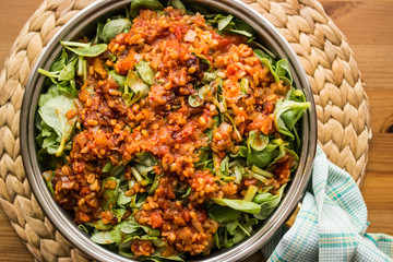 Purslane food with tomato sauce in a pan on a wicker.