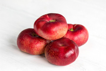 Fresh flat peach fruits on white wooden table