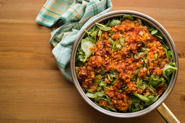 Purslane food with tomato sauce in a pan on a wicker.
