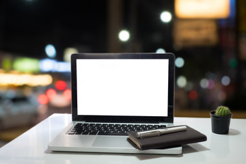 Blank screen of Laptop on wood work table in blurred night citys