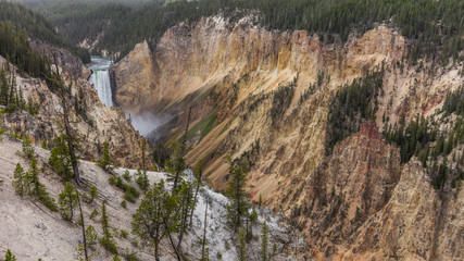 Stormy river flows in a narrow gorge in the rocks. Big waterfall among the beautiful rocks. Mountain landscape. Uncle Toms Trail on The Grand Canyon of the Yellowstone National Park, Wyoming