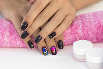 Hands girl with beautiful manicure on a pink towel with a set of cosmetics.