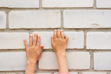 Children's hand trying to grab the tabs brick wall