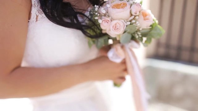 Close-up portrait of brunette bride walking on the city street and lovely looking at camera