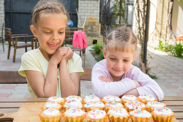 Fototapeta premium Two sisters with an appetite for looking at home-baked Easter cakes