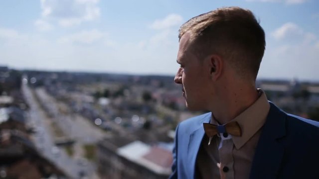 Happy handsome groom in blue suit looking at old european architecture