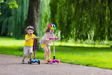 Little kids riding colorful scooters