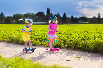 Kids riding scooter on sunny summer day