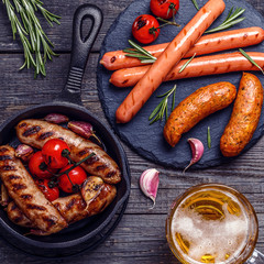 Grilled sausages with glass of beer on wooden table.