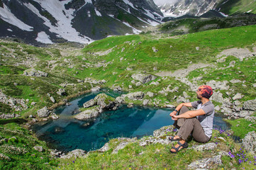 Young man admires the mountain lake.