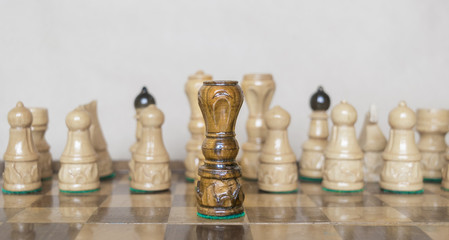 Black queen in front of white figures on chess table.