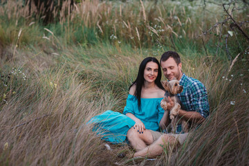 Young happy attractive couple posing with their dog - yorkshire terrier on nature,love,lifestyle,relationship 