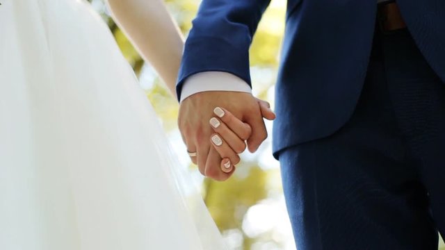 Wedding couple holding hands with rings on green nature background