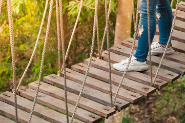 tourist walking away on a wooden suspension bridge , cross to the other side forest