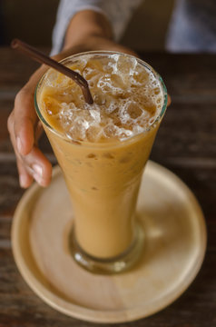 Glass of iced coffee against women's hand. Selective Focus.