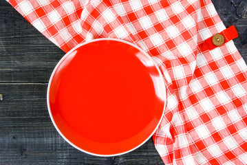 Background: white textured surface of the table, a tablecloth on it in red cell and big round cutting board