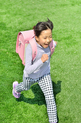 芝生広場で走る小学生の女の子(ランドセル)