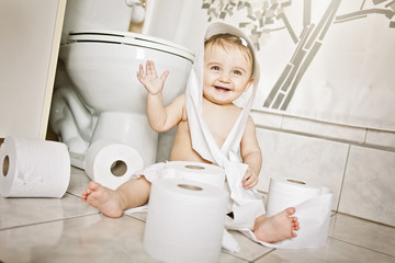 Toddler ripping up toilet paper in bathroom