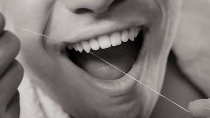 Young man cleaning her white teeth with dental floss